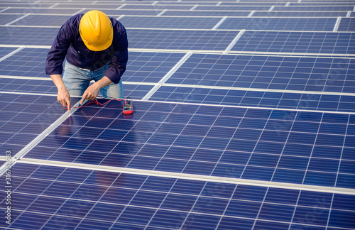 Electrician working on measurement Voltage at solar cell on building roof ,  Renewable energy Concept.