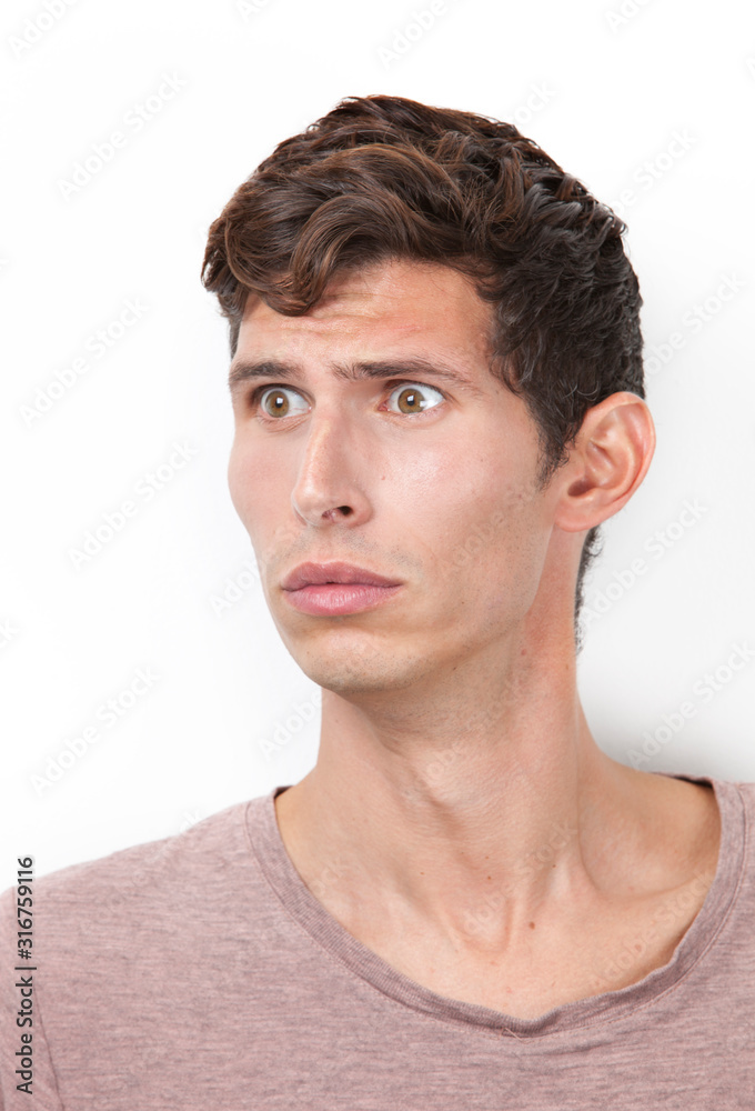 Shocked young man looking away against white background Shocked young man looking away against white background