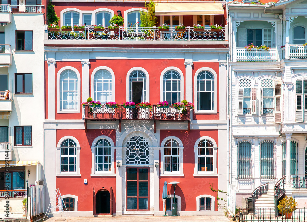 Colorful red mansion  with arched windows and beautiful balconies with flowers. Classic architecture buildings facades.