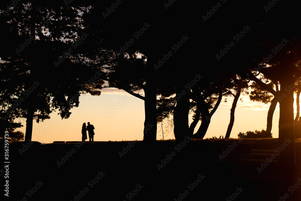 Silhouettes of unrecognizable people enjoying the sunset in Sustipan park in Split, Croatia.