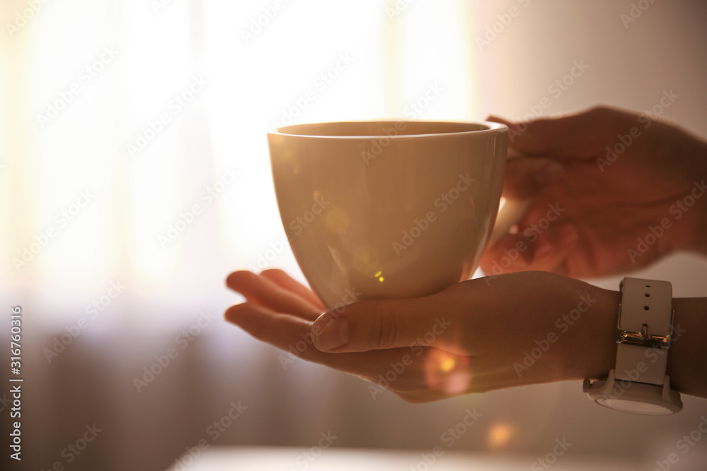 Woman holding cup of drink on blurred background, closeup. Lazy morning - obrazy, fototapety, plakaty 