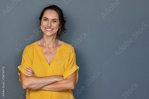 Happy mature woman smiling on grey wall photo