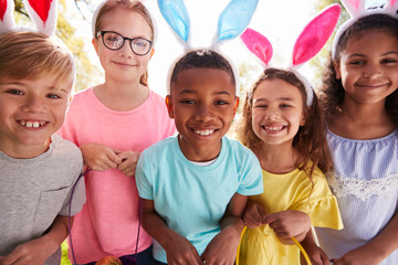 Portrait Of Five Children Wearing Bunny Ears On Easter Egg Hunt In Garden