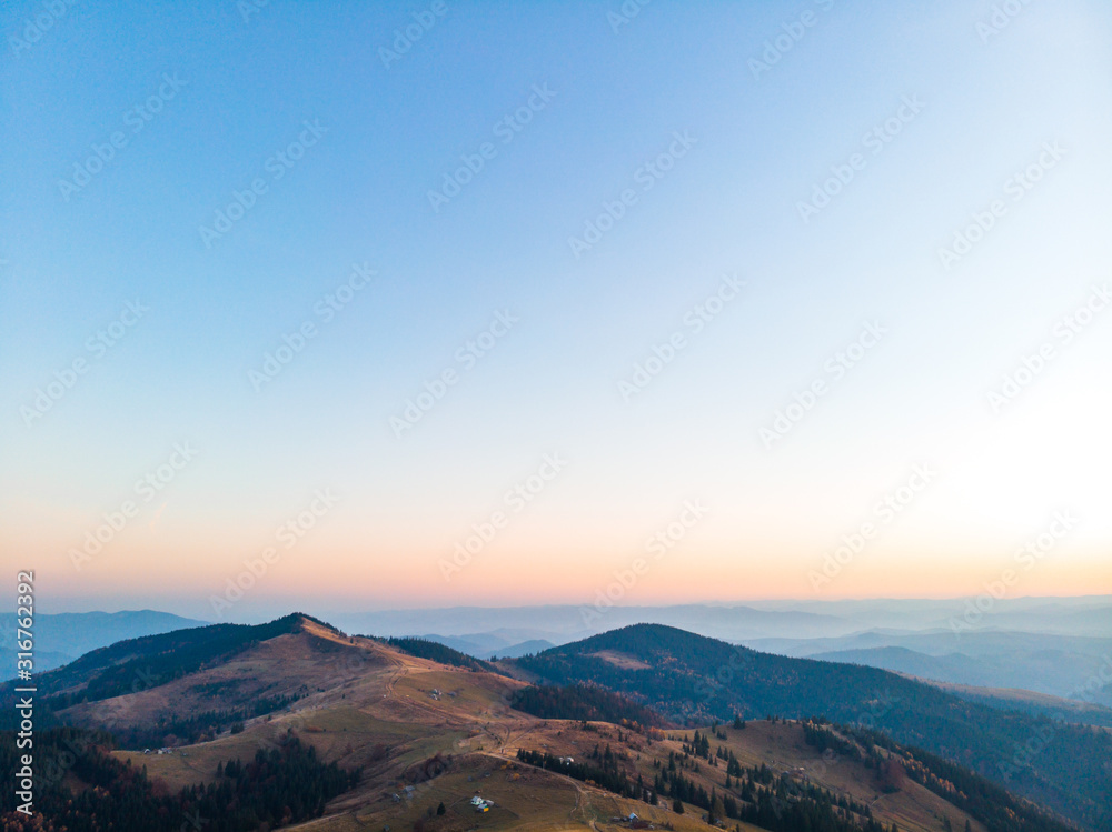 Aerial view of the Carpathian mountains in autumn. Pine forest, houses on the peaks, yellow fields and trees. Mountain meadow. sunset, Ukraine, Europe Aerial view of the Carpathian mountains in autumn. Pine forest, houses on the peaks, yellow fields and trees. Mountain meadow. sunset, Ukraine, Europe