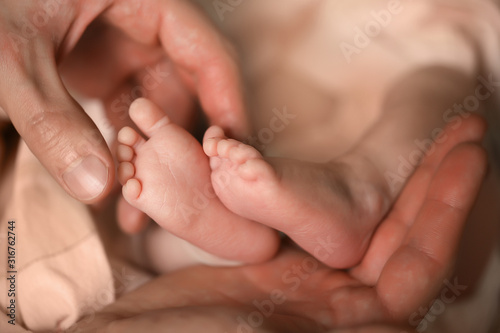 Heels of a newborn baby in the hands of a man