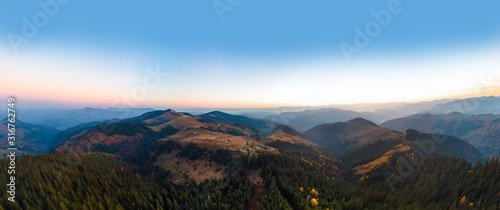 Aerial view of the Carpathian mountains in autumn. Pine forest, houses on the peaks, yellow fields and trees. Mountain meadow. sunset, Ukraine, Europe © Sergey