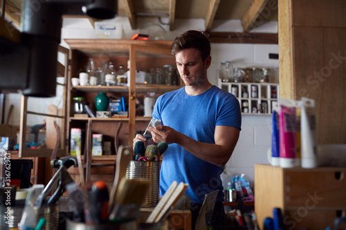 Man In Workshop Choosing Paintbrush For Upcycling And Craft Projects