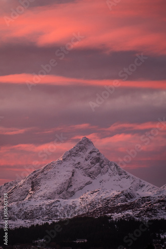 sunrise at lofoten islands mountains. peaks during winter sunrise. pinky and red light with peak and mountains under snow. skottinden and himmeltindan