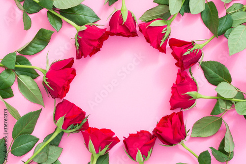 A frame made of red roses on pink background