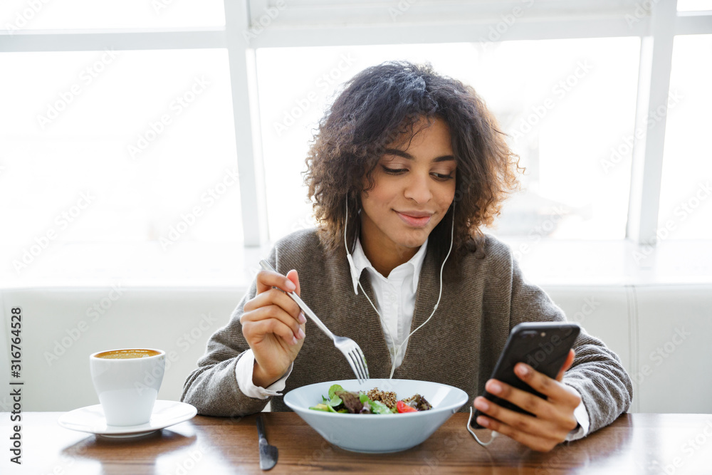 Portrait of african american woman with earphones and cellphone in cafe Portrait of african american woman with earphones and cellphone in cafe