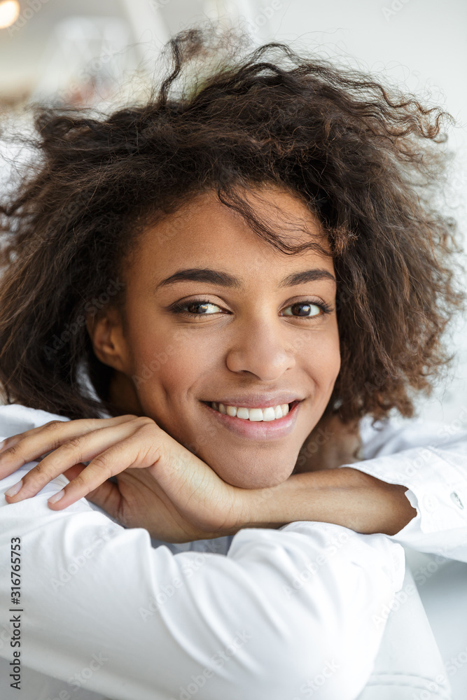 Portrait of young african american woman sitting on sofa in bright room