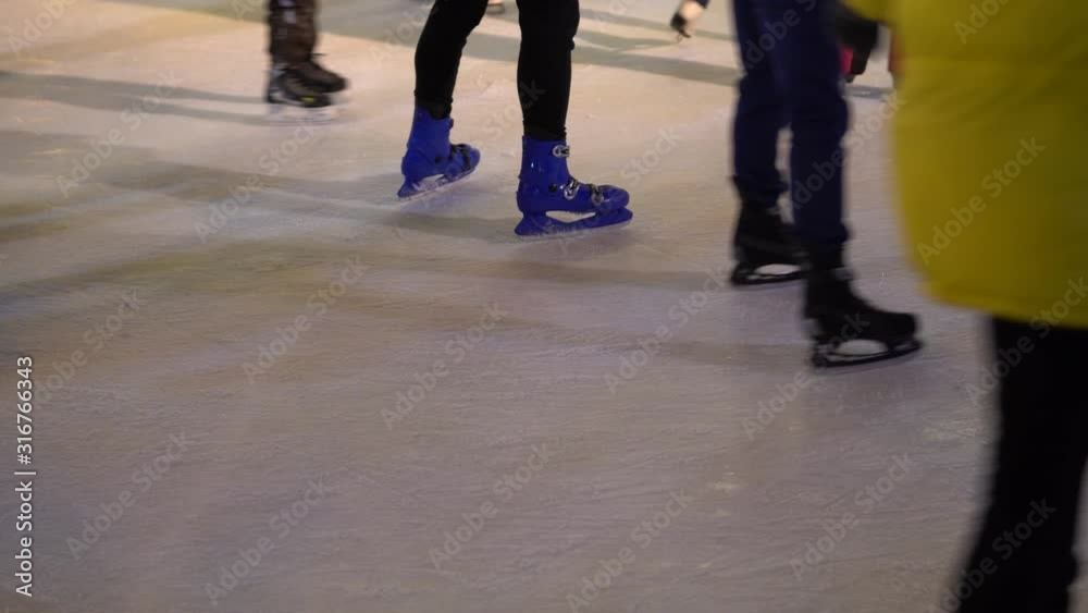 People on ice skating rink outdoors, focus on the sliding feet People on ice skating rink outdoors, focus on the sliding feet