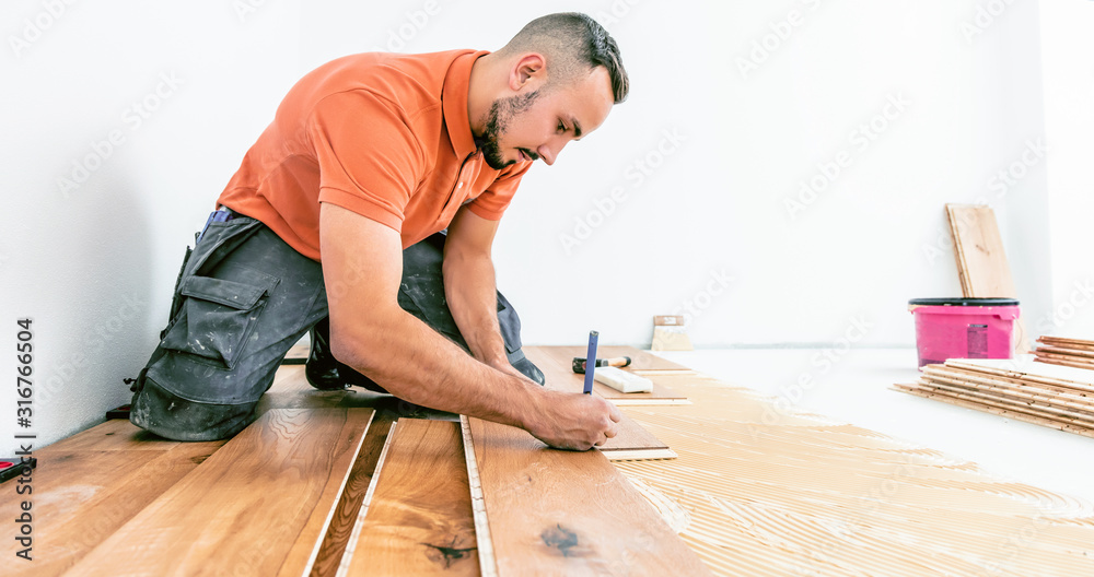 Fototapeta premium Handwerker verleget Parkett boden in einem modernen neubau Haus