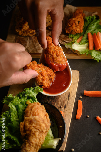 Fotografia Two hand holding crispy fried chicken dipped in tomato sauce