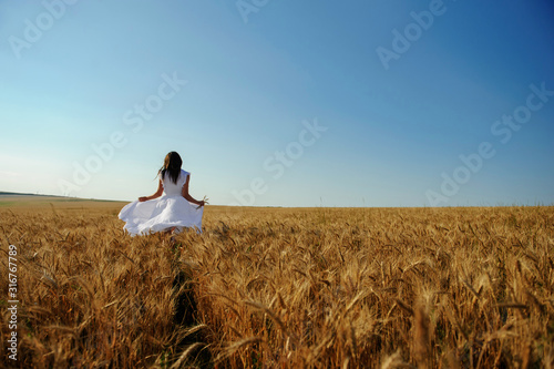 back view of a woman in white dress in wheat field