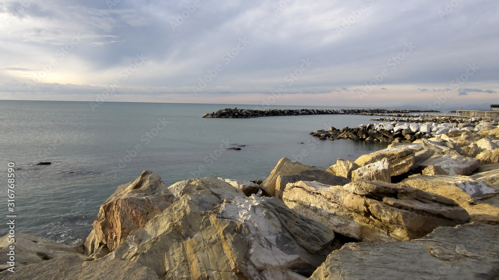 beautiful pastel view of the rocky beach and slightly cloudy sky on a quiet day by the sea beautiful pastel view of the rocky beach and slightly cloudy sky on a quiet day by the sea