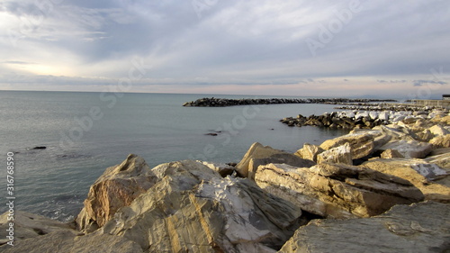 beautiful pastel view of the rocky beach and slightly cloudy sky on a quiet day by the sea