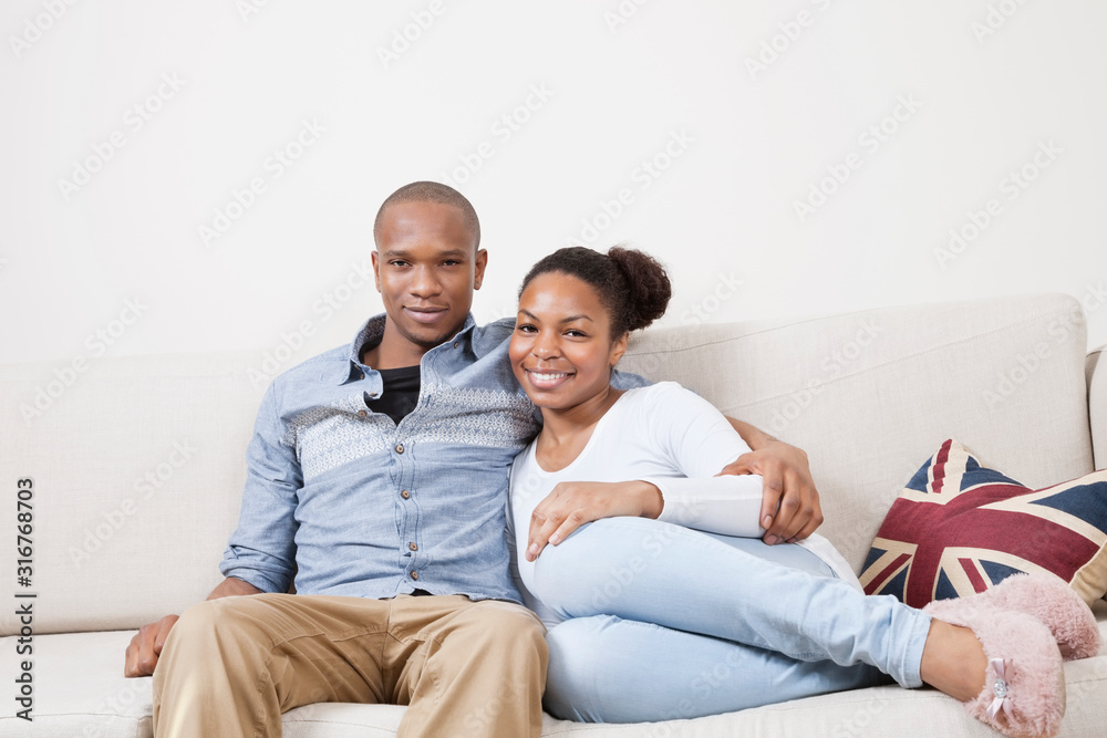 Portrait of happy African American young couple relaxing on sofa Portrait of happy African American young couple relaxing on sofa