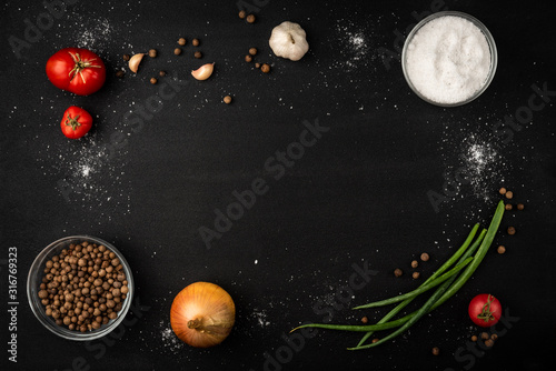 Onion, tomatoes, garlic, potato and black pepper on black background.