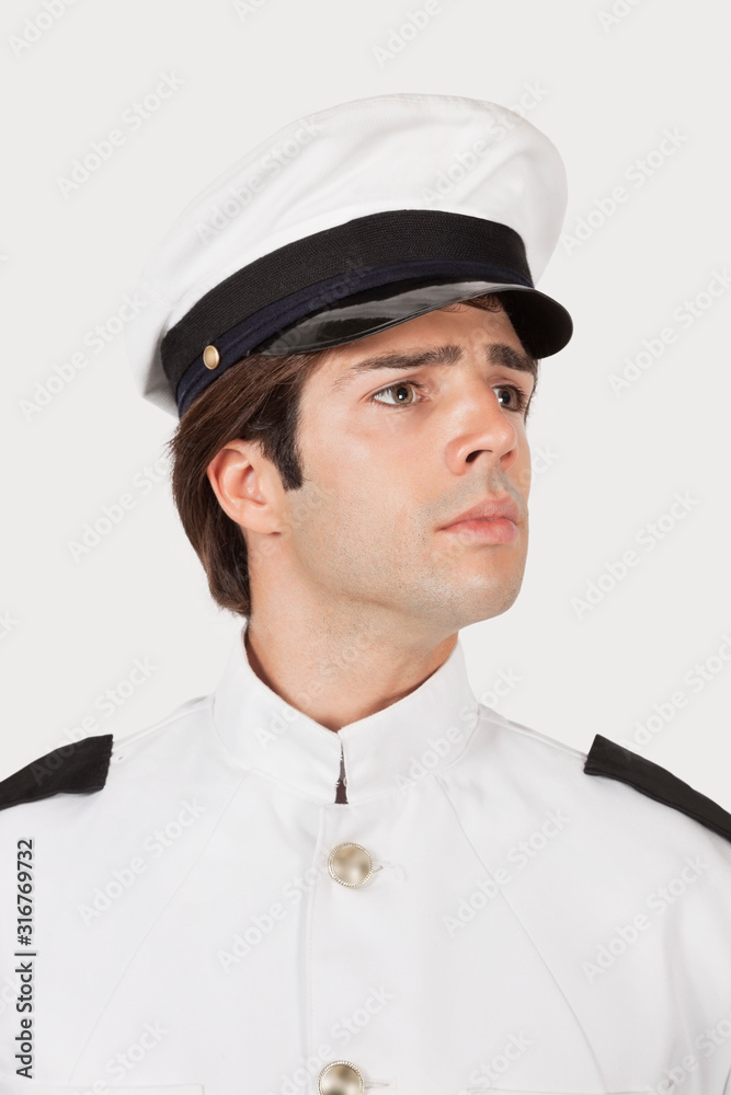Young navy officer looking away against gray background