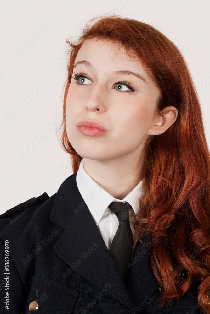 Thoughtful young woman in police officer's costume against gray background Thoughtful young woman in police officer's costume against gray background
