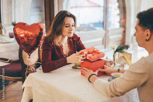 Man presenting gift to his girlfriend at Valentine's Day. photo