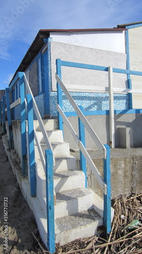 Steps leading from the beach to the cabins by the sea in blue and white.