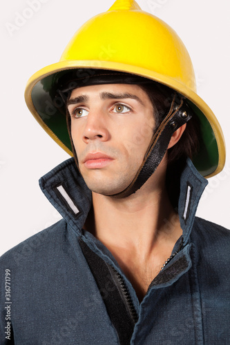 Thoughtful fireman looking away against gray background © moodboard