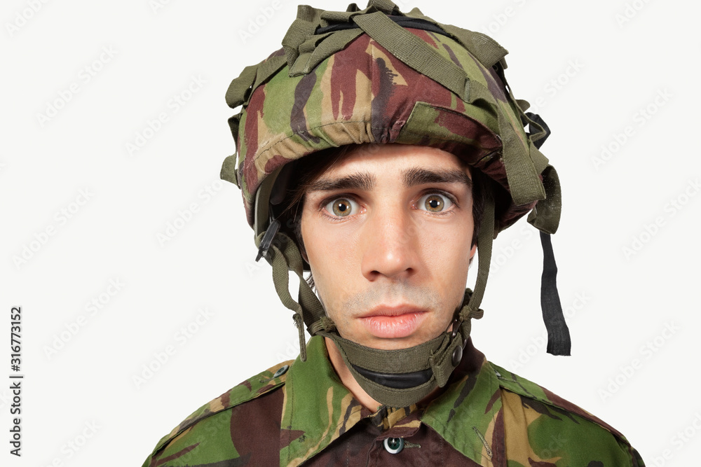 Close-up portrait of young soldier staring against gray background Close-up portrait of young soldier staring against gray background