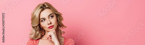 panoramic shot of pensive girl looking away while holding hand near chin on pink background