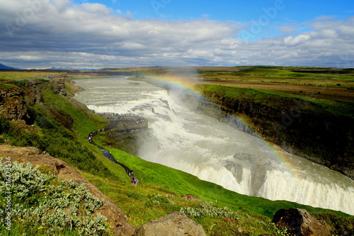 Beautiful view of Gullfoss waterfalls of Iceland with mist and rainbow above the tourists in the summer