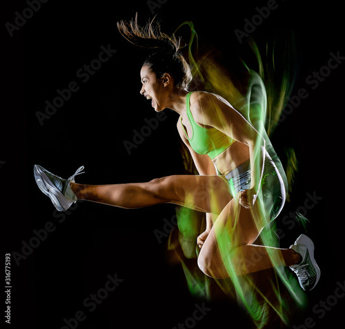 woman exercising fitness exercises isolated black background lightpainting effect © snaptitude