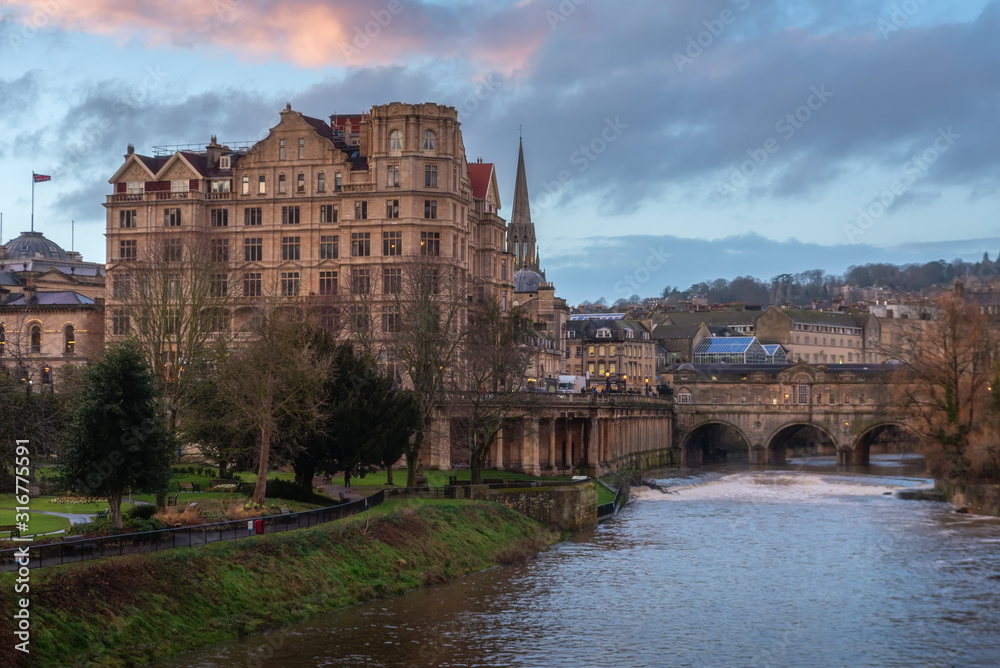 View of Avon river with Pulteney bridge and historical building background during sunset at Bath, UK