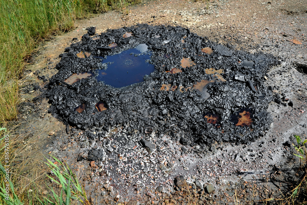 Fototapeta premium Active mud (clay and bitumen) volcano on the outskirts of the village Starunja in Carpathian. Spills of crude oil on the soil surface. Crater of the mud volcano.