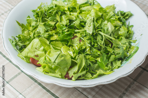 Fresh green salad of tomato and cucumber in plate on kitchen table.