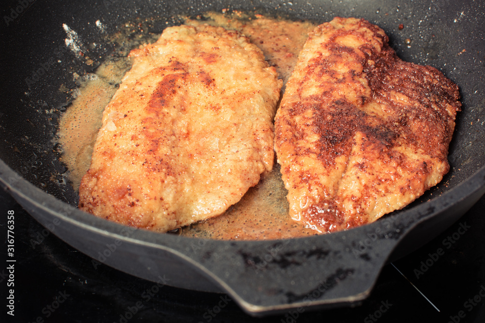 Tilapia fish fillets rolled in flour and breadcrumbs to roast in pan.