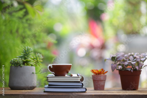 Brown coffee cup with notebooks and plants at outdoor