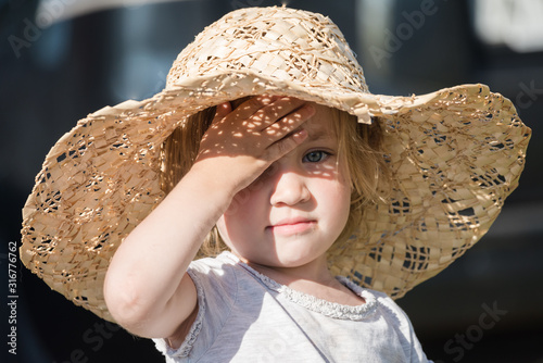 Small child in big hat takes cover from the sun so as not to burn out.