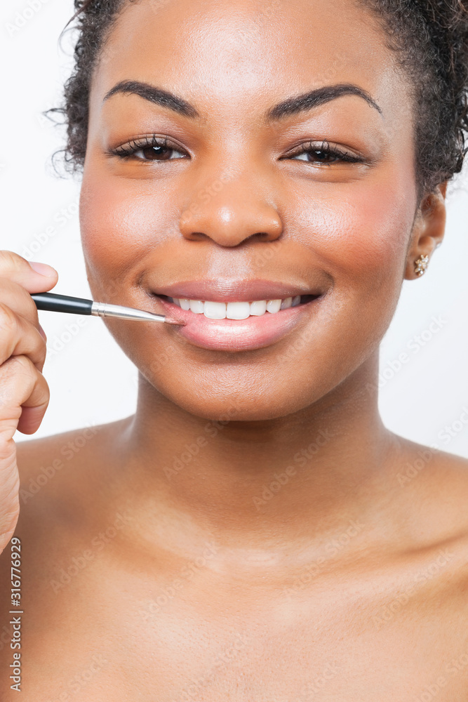 Close-up portrait of young woman applying lip gloss with brush Close-up portrait of young woman applying lip gloss with brush