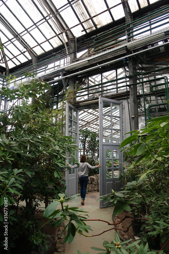 A girl standing near the door to the greenhouse with evergreen