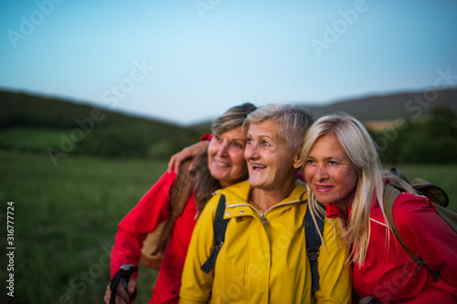 Senior women friends on walk outdoors in nature at dusk.