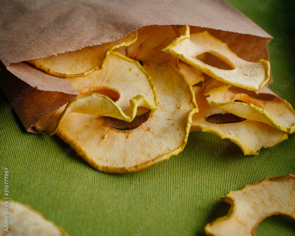 Dried apple slices in craft paper package on green background