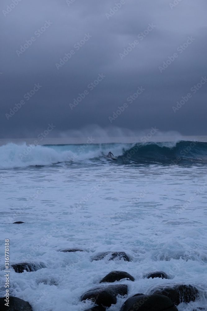 Surfer ride a wave in Unstad beach area which is known as an arctic surfing center located in Lofoten Islands in Northern Norway. 