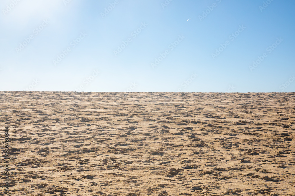 Blue sky over a golden yellow sand dune with a lot of structures and shapes close to a beach where pople enjoy a sunbath and their holiday vacation travel Blue sky over a golden yellow sand dune with a lot of structures and shapes close to a beach where pople enjoy a sunbath and their holiday vacation travel