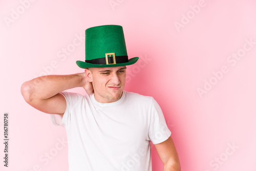 Young caucasian man celebrating saint patricks day touching back of head, thinking and making a choice.