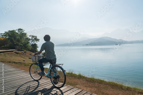 young men riding a bicycle on bike trail at the lake in the morning. Active people. Outdoors