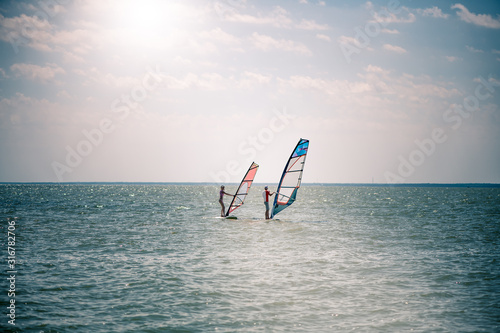 Romance in the sea couple man and woman together sailing on a windsurfing board while on vacation in south