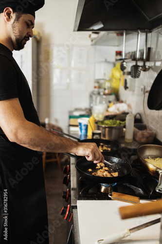 Professional chef working in restaurant kitchen and making delicious traditional food.