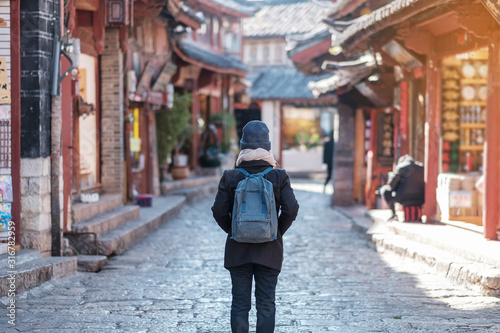 young woman traveler traveling at the Square street in Lijiang Old Town, landmark and popular spot for tourists attractions in Lijiang, Yunnan, China. Asia travel concept © Jo Panuwat D
