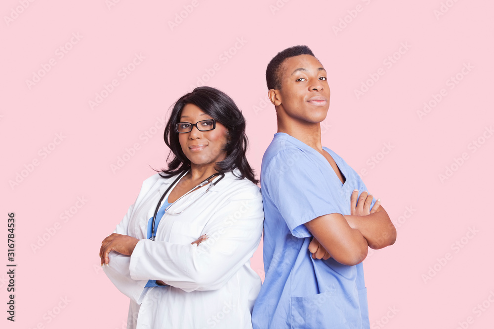 Portrait of confident mixed race male and female surgeons over pink background Portrait of confident mixed race male and female surgeons over pink background
